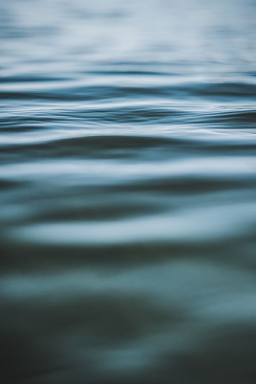 Free Serene capture of blue water with soft ripples and reflections, creating a peaceful and calm atmosphere. Stock Photo