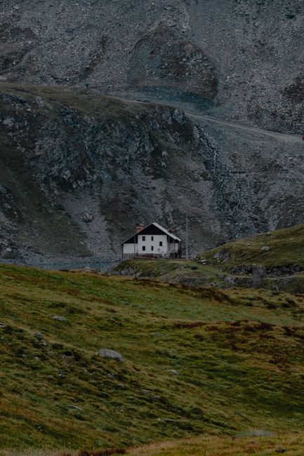 A solitary cabin nestled against a rocky mountainside in a serene, natural landscape.
