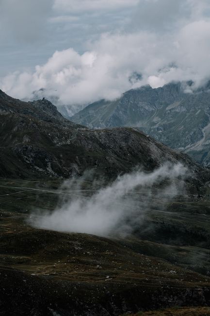 A scenic view of misty mountains with clouds enveloping peaks during an overcast day.