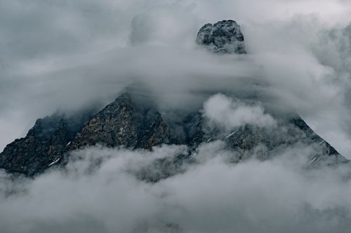 Free A dramatic photograph of a mountain peak enveloped in mist and clouds, creating a moody atmosphere. Stock Photo