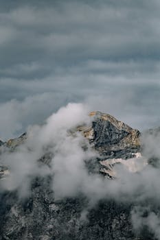 A majestic mountain peak shrouded in clouds, creating a dramatic and moody atmosphere.