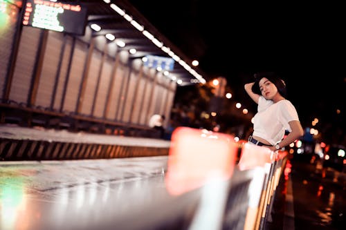 Photo of Woman Posing While Leaning on Railing at Night