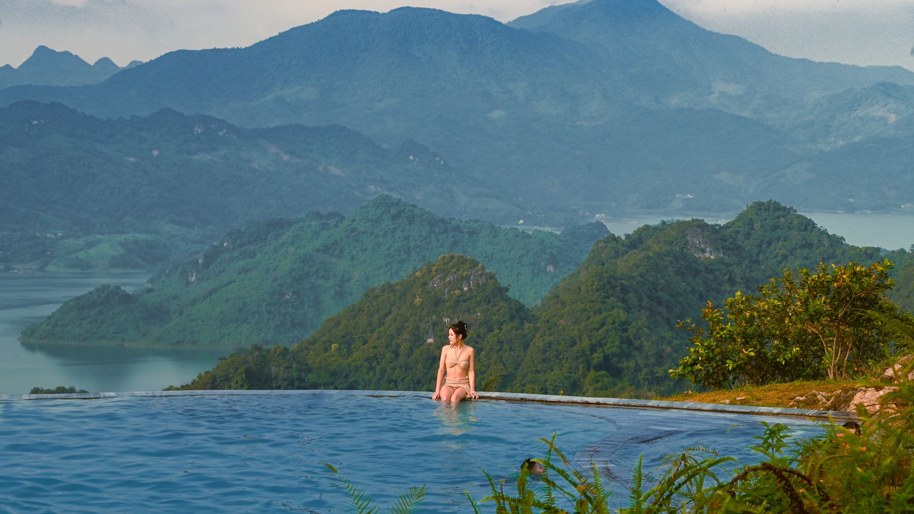 A woman enjoying leisure at an infinity pool with stunning views of Sơn La mountains.