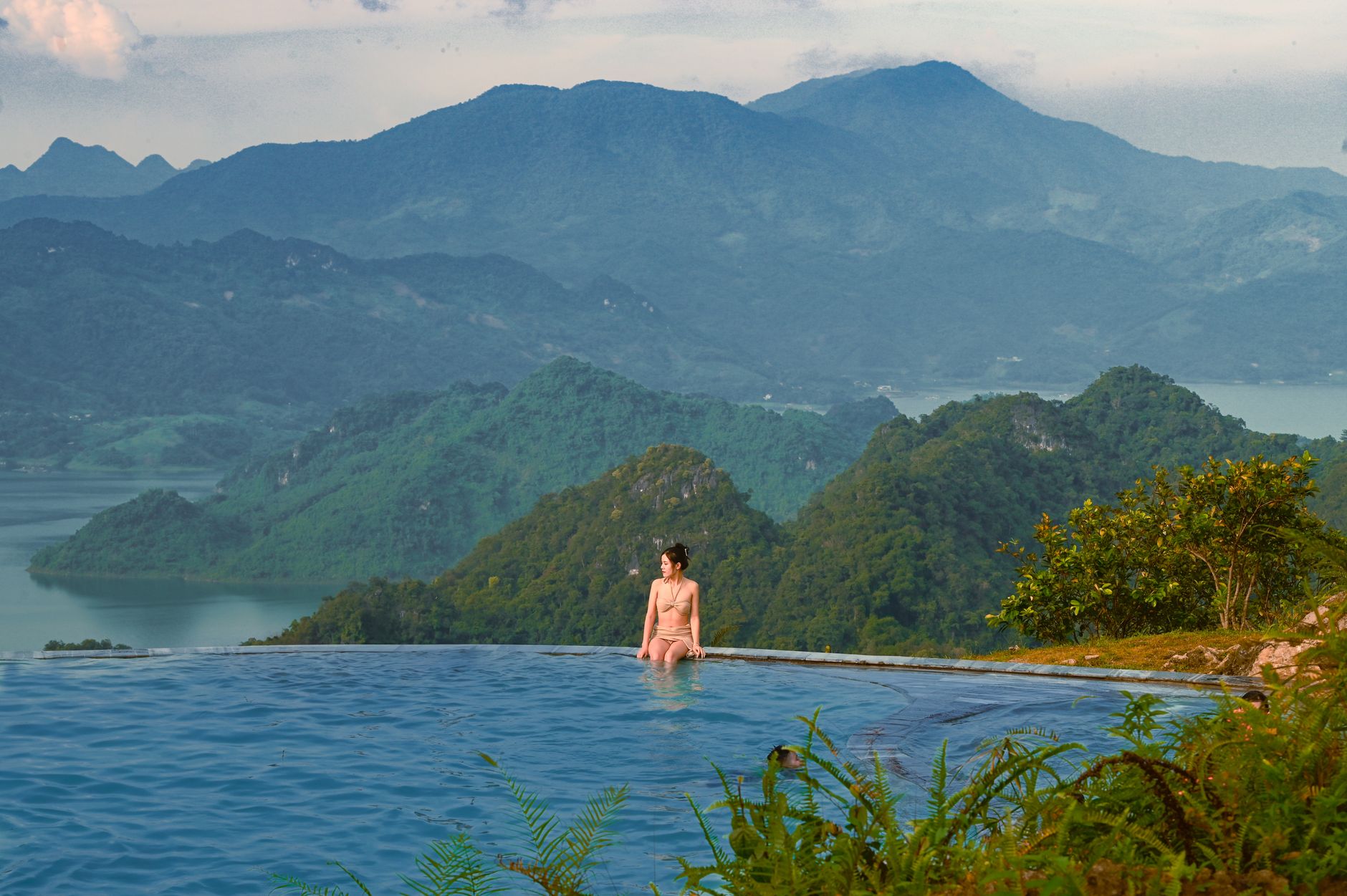 A woman enjoying leisure at an infinity pool with stunning views of SΖ‘n La mountains.