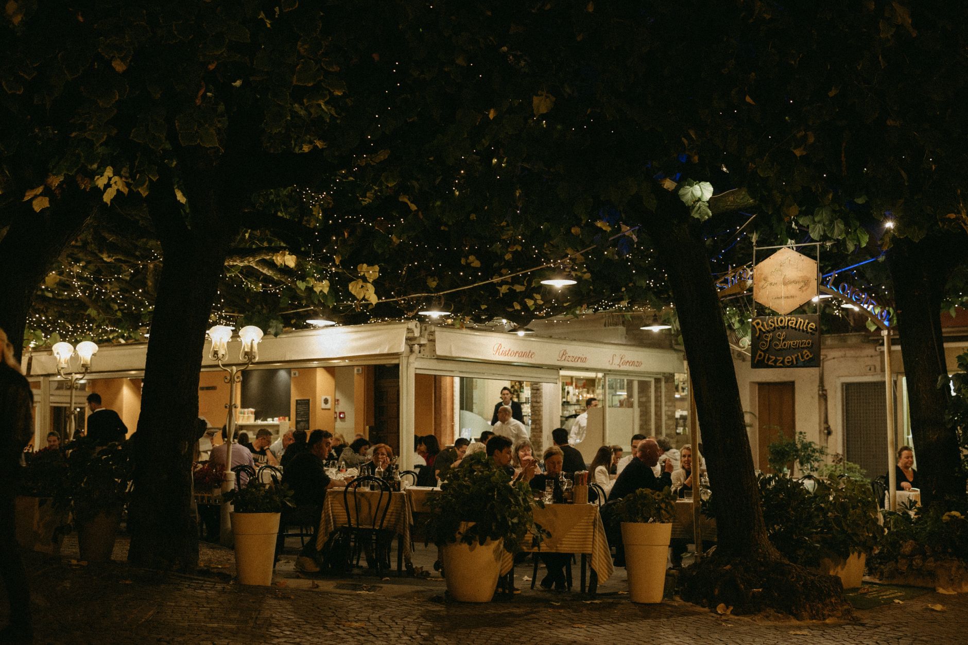 Cozy outdoor dining with warm lights at an evening Italian restaurant.
