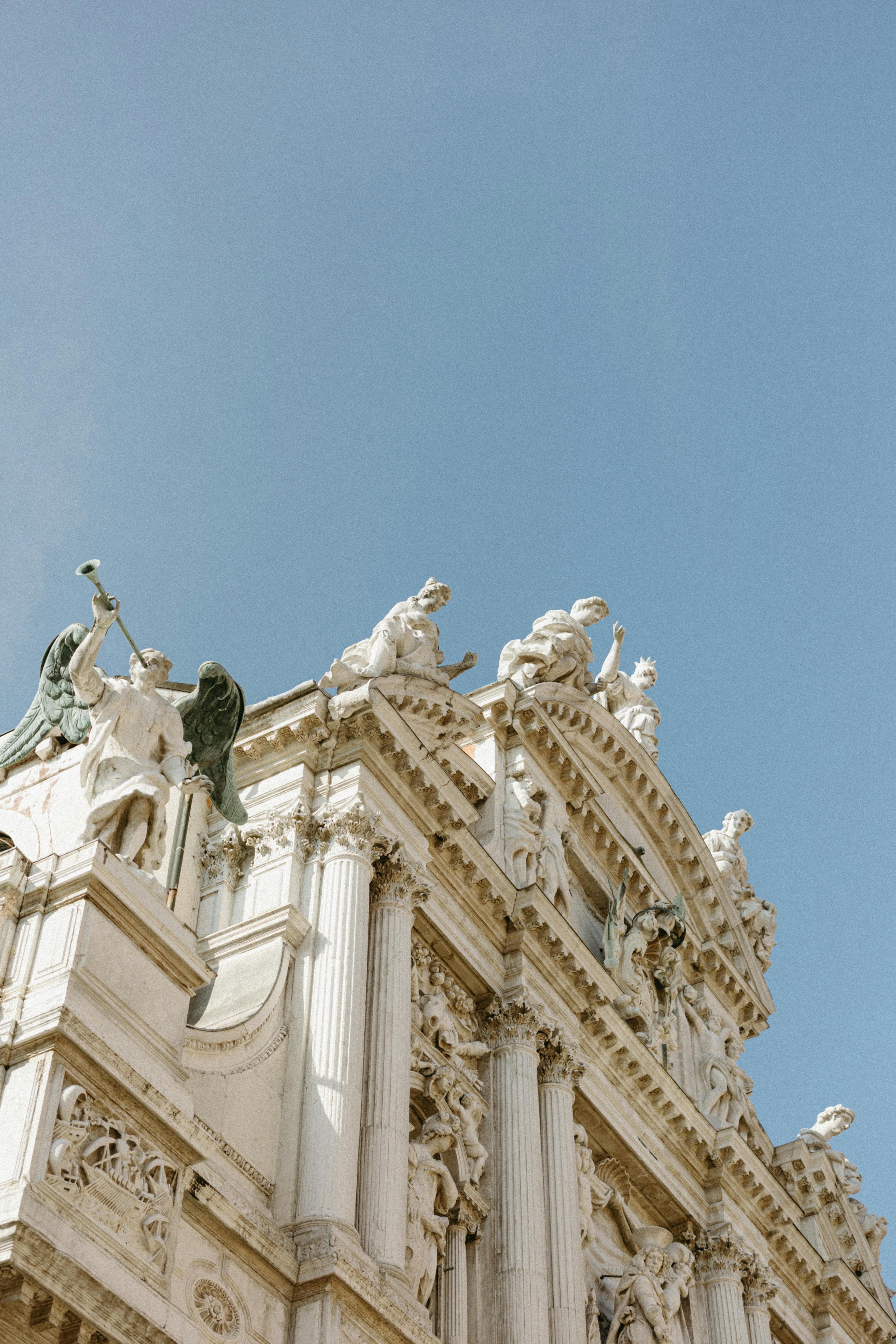 Elegant facade of an ancient building with detailed sculptures under a clear blue sky.