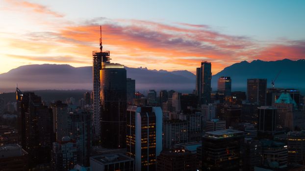 Stunning Vancouver cityscape with glowing sunset and mountain backdrop, showcasing modern architecture.
