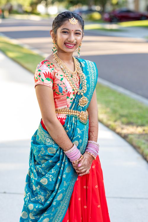 Free A young woman in vibrant Indian attire with jewelry, smiling outdoors, representing culture and festivity. Stock Photo