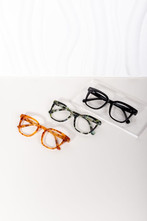 Free A minimalistic flat lay of three stylish eyeglasses in varying designs and colors on a white surface. Stock Photo
