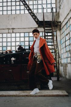Stylish adult in orange coat and white sneakers captured in an industrial location, RJ, Brasil.