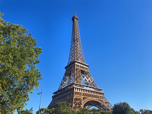 Free The iconic Eiffel Tower adorned with the Olympic rings under a clear blue sky in Paris, France. Stock Photo