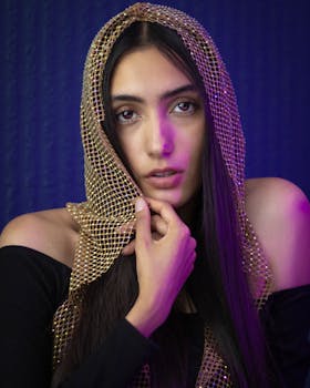 Serene portrait of a young woman posing elegantly with a gold net veil.