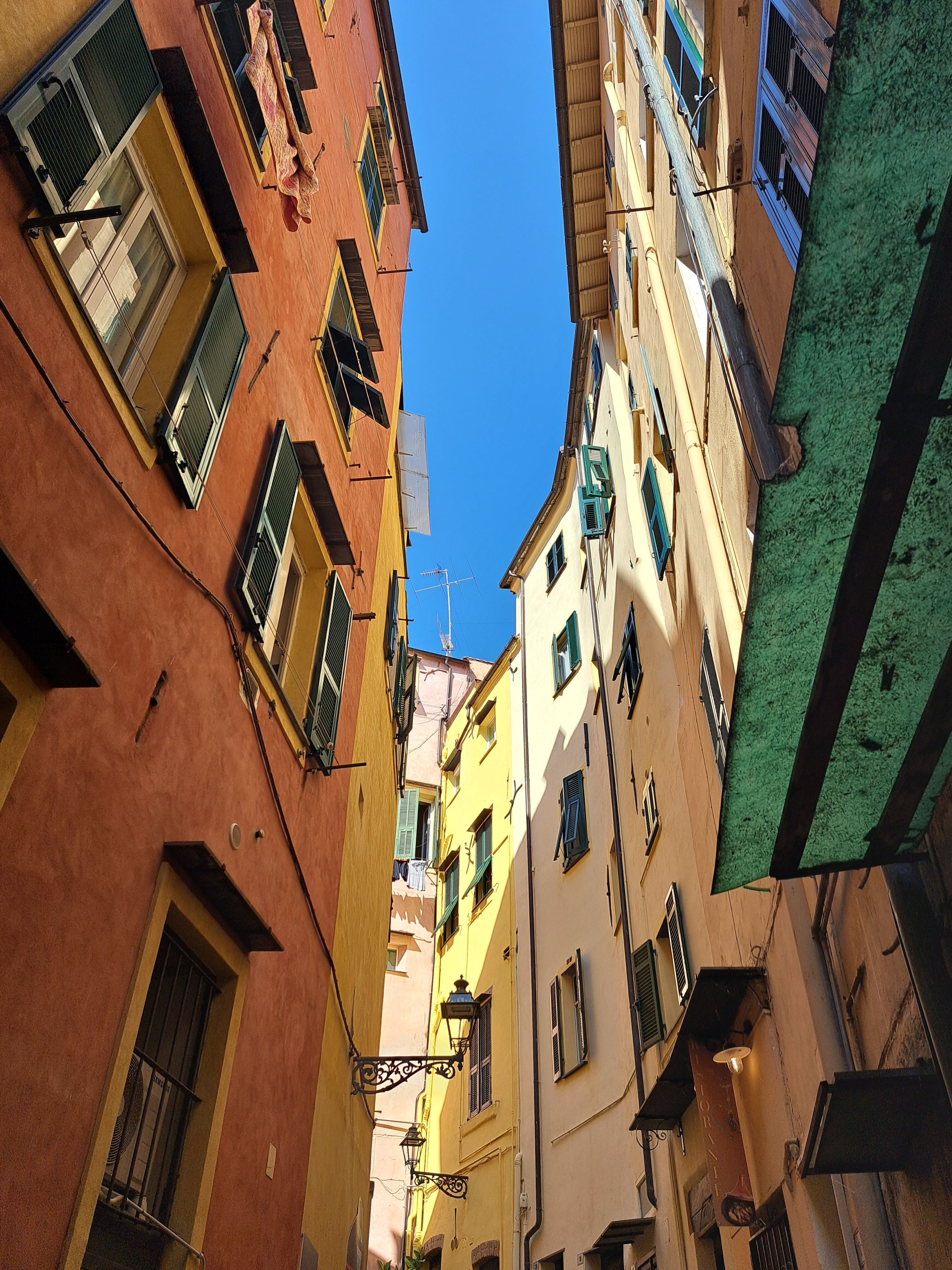 Colorful buildings in a narrow alleyway of Sanremo, showcasing Ligurian architecture under a bright blue sky.