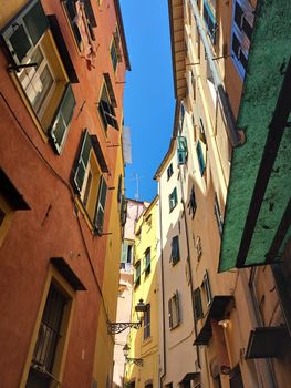 Colorful buildings in a narrow alleyway of Sanremo, showcasing Ligurian architecture under a bright blue sky.