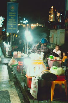 Vibrant night market in Dalat, Vietnam with street vendors and bright lights, capturing local culture.
