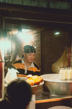 A street vendor in Dalat, Vietnam, prepares food at a night market, showcasing local cuisine.