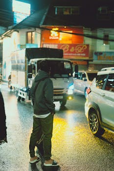 A man stands in traffic at night on a rainy street in Dalat, Vietnam.