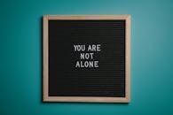 You Are Not Alone Quote Board on Brown Wooden Frame