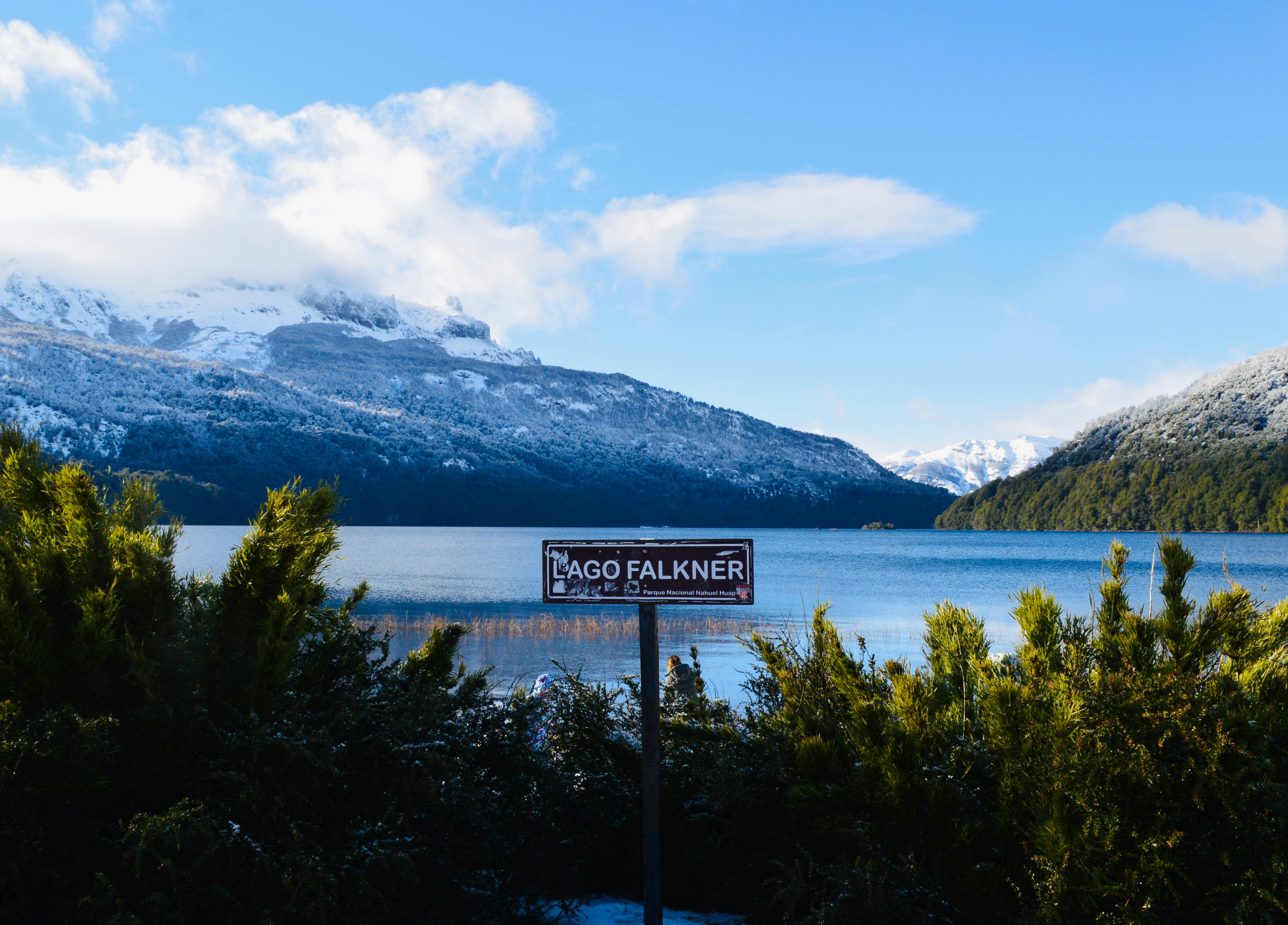 Discover the serene beauty of Lago Falkner in Neuquén, Argentina with snowy mountains and clear waters.