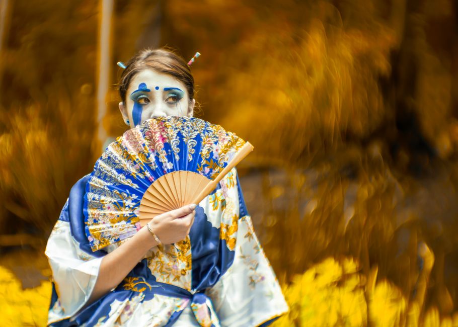 A stunning portrait showcasing a woman in traditional Japanese attire with striking makeup, outdoors.