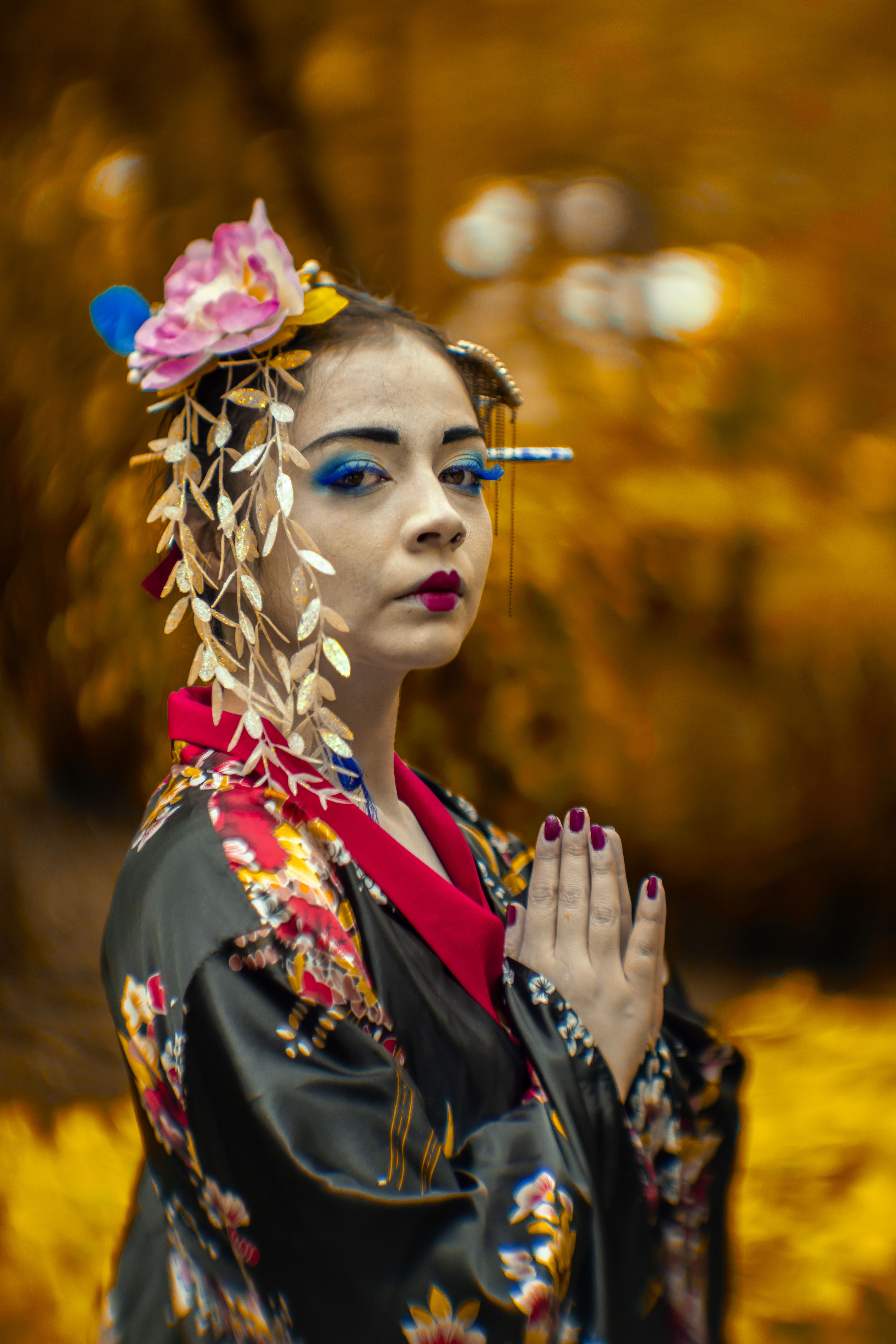 A woman in a black floral kimono poses outdoors amid fall foliage in Ciudad de México.