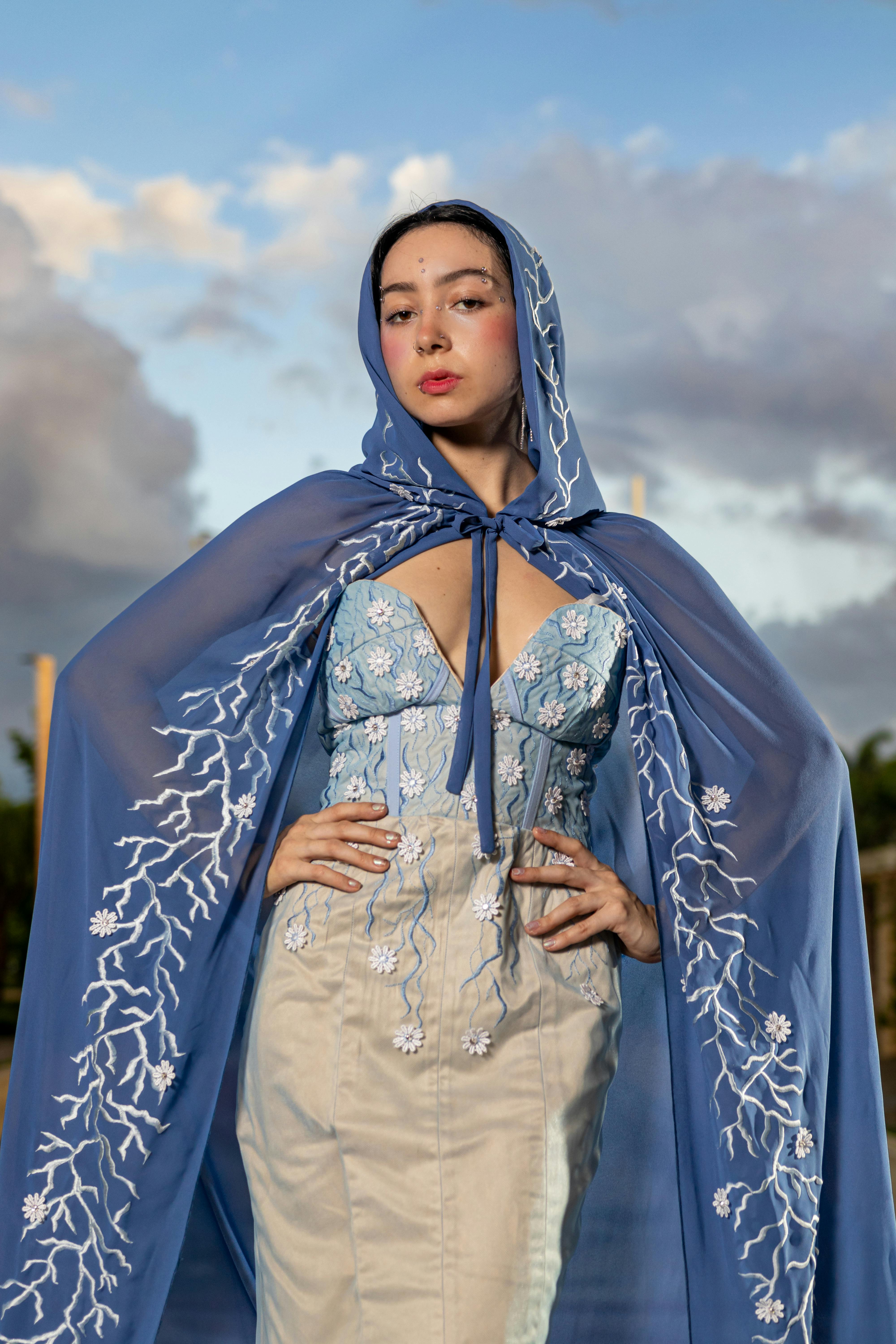 a woman in a blue cape and dress