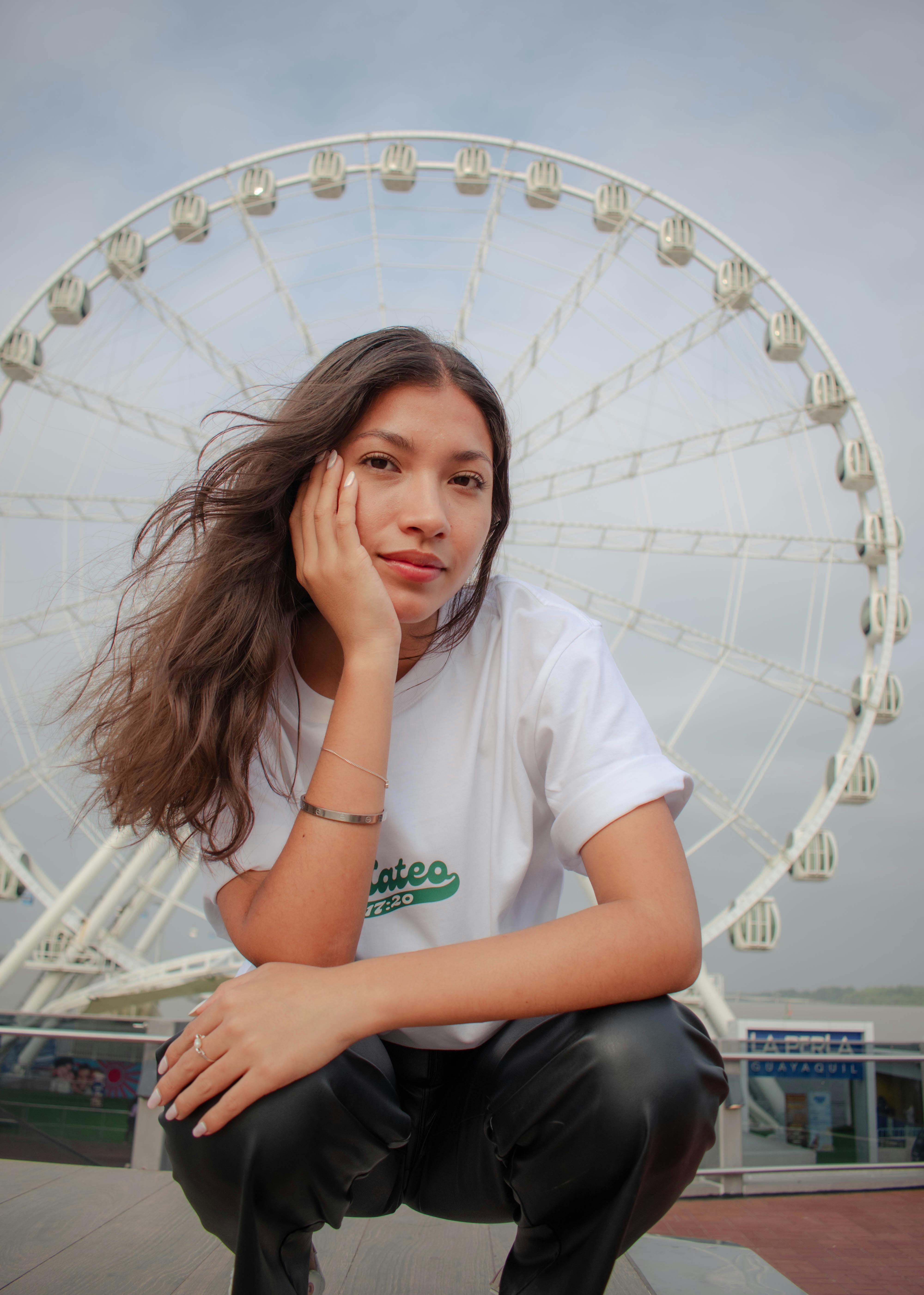 a woman sitting on the ground in front of a ferris wheel