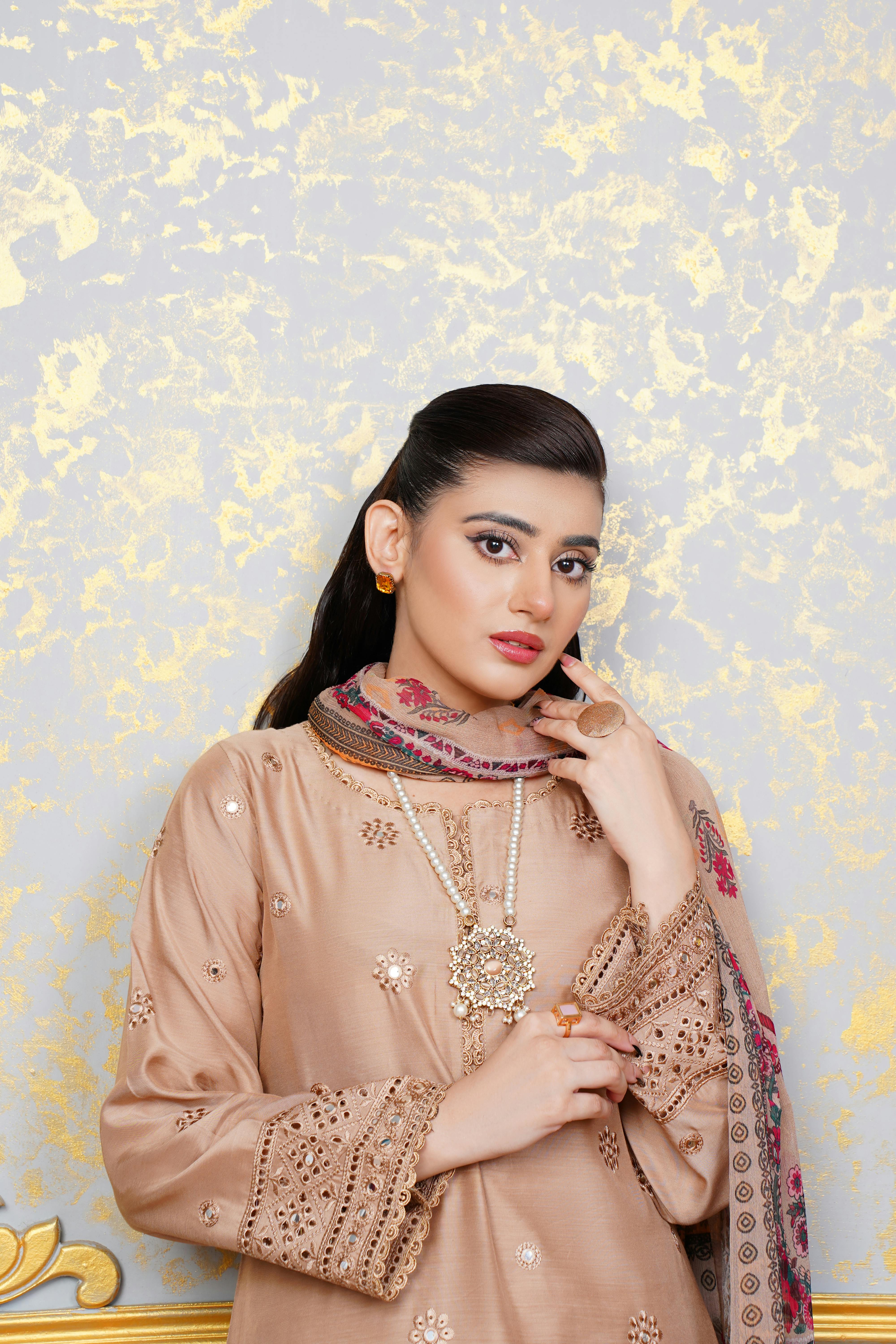 Portrait of a young woman in elegant traditional Pakistani attire with jewelry, photographed indoors.