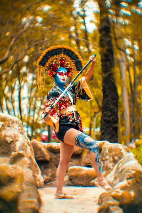 Free Person in traditional costume with painted face and sword in a vibrant forest scenery. Stock Photo