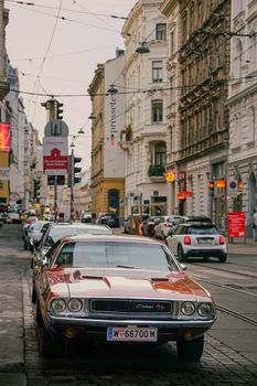 A vintage car parked on a bustling European city street with historic buildings.