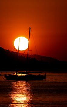 A stunning silhouette of a sailboat at sunset on the Mediterranean Sea in Beaulieu-sur-Mer, France.