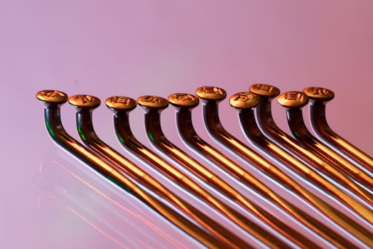 Detailed view of glossy metal hooks aligned on a vibrant pink backdrop.