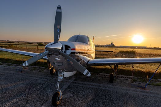 A private aircraft parked on the tarmac at Sylt Airport with a beautiful sunset in the background.