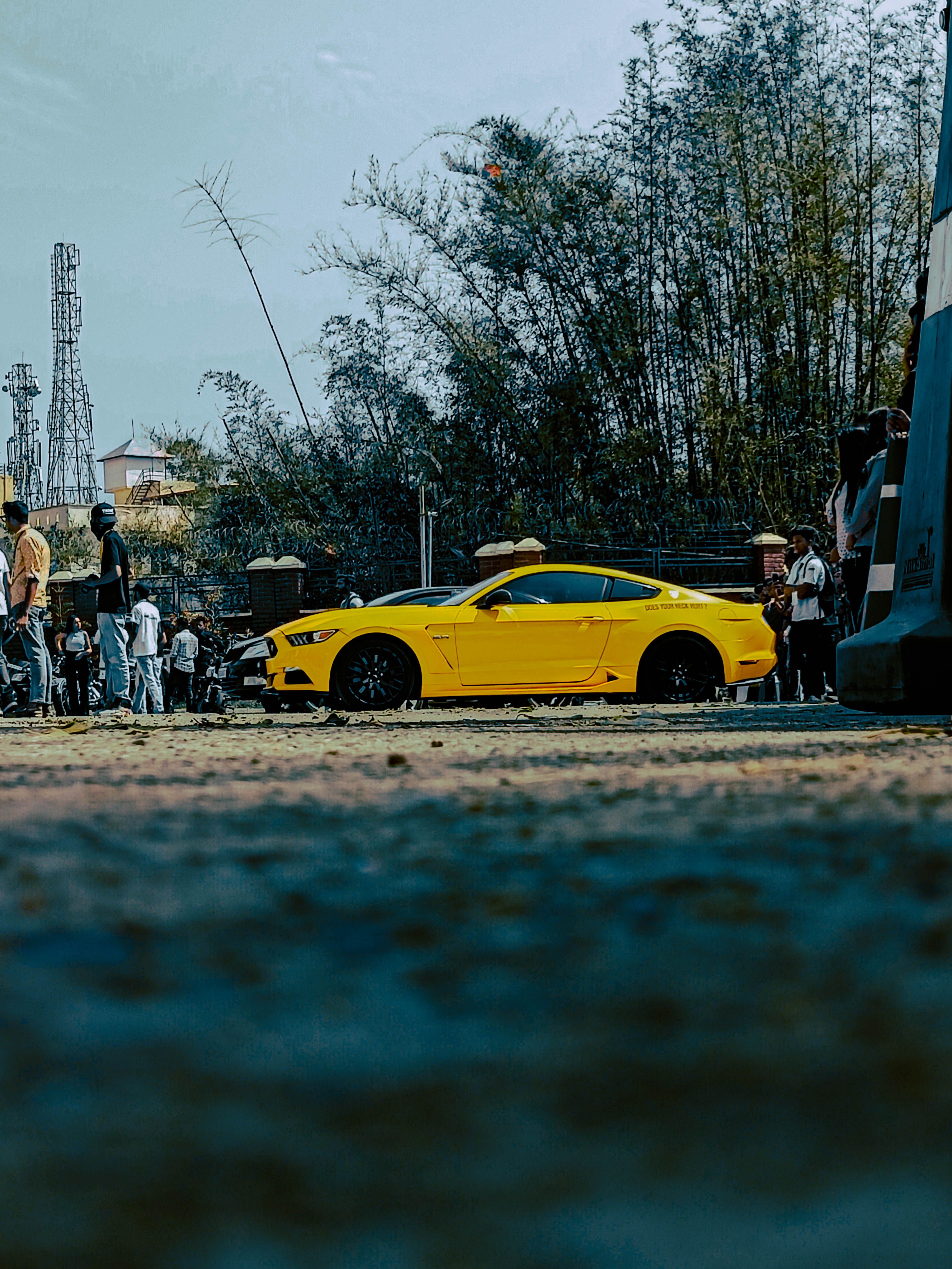 A striking yellow Ford Mustang parked outdoors at an event in Dehradun, India.