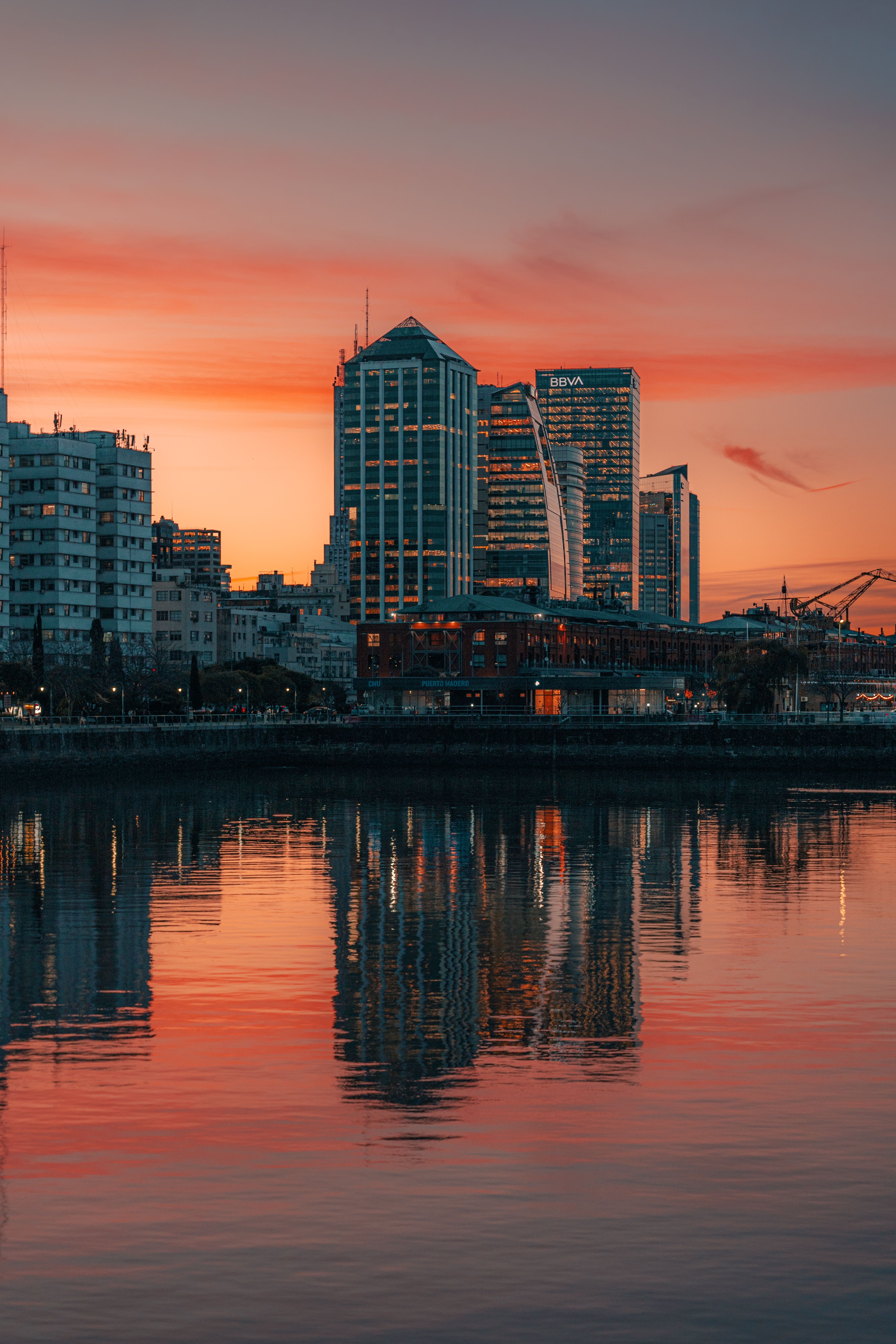 A sunset over the city skyline with buildings reflected in the water ...