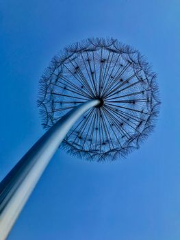 Low angle view of a dandelion-inspired metal sculpture under a clear blue sky, Dubai.