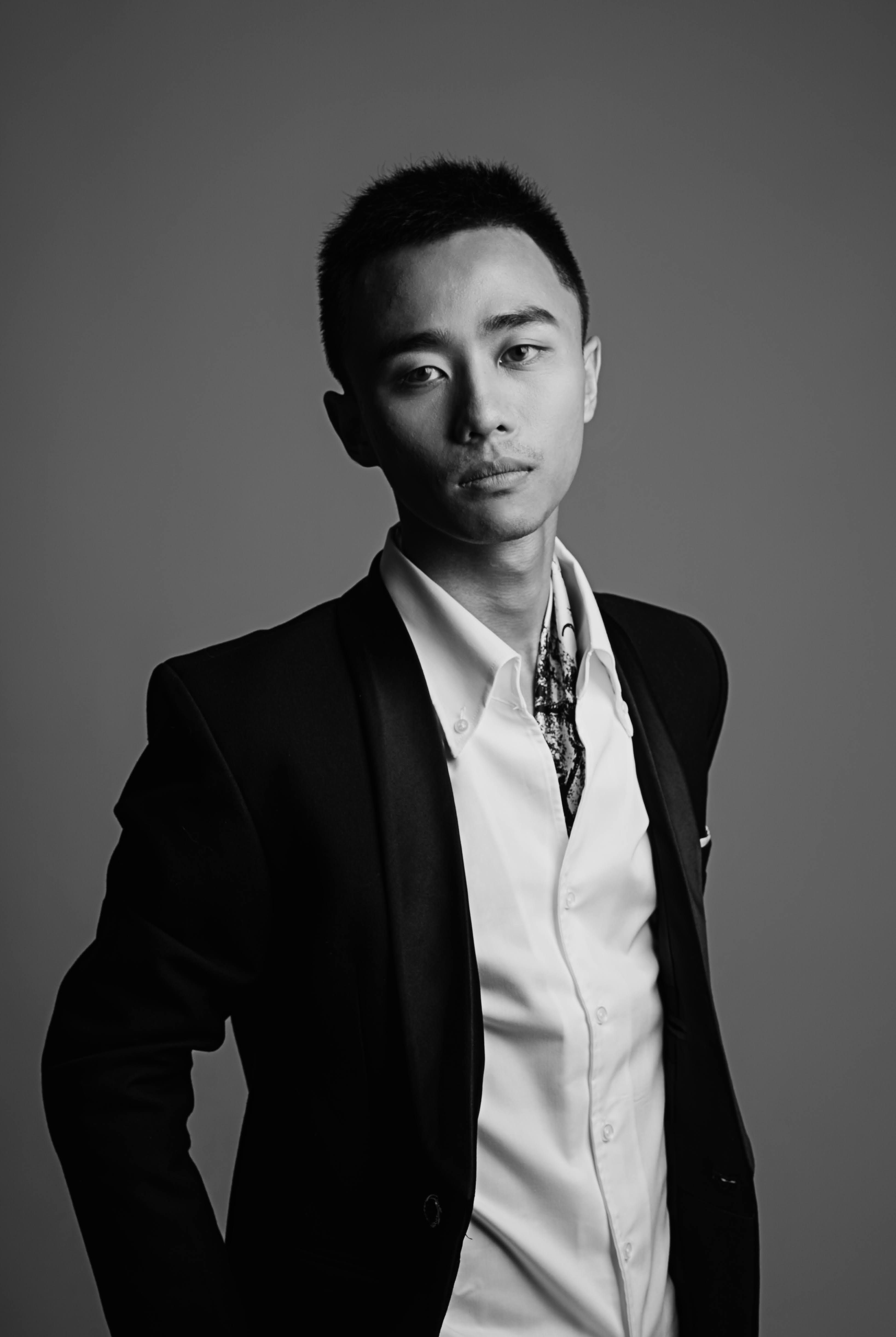 Free Black and white portrait of a young man in a tuxedo posing confidently in a studio setting. Stock Photo
