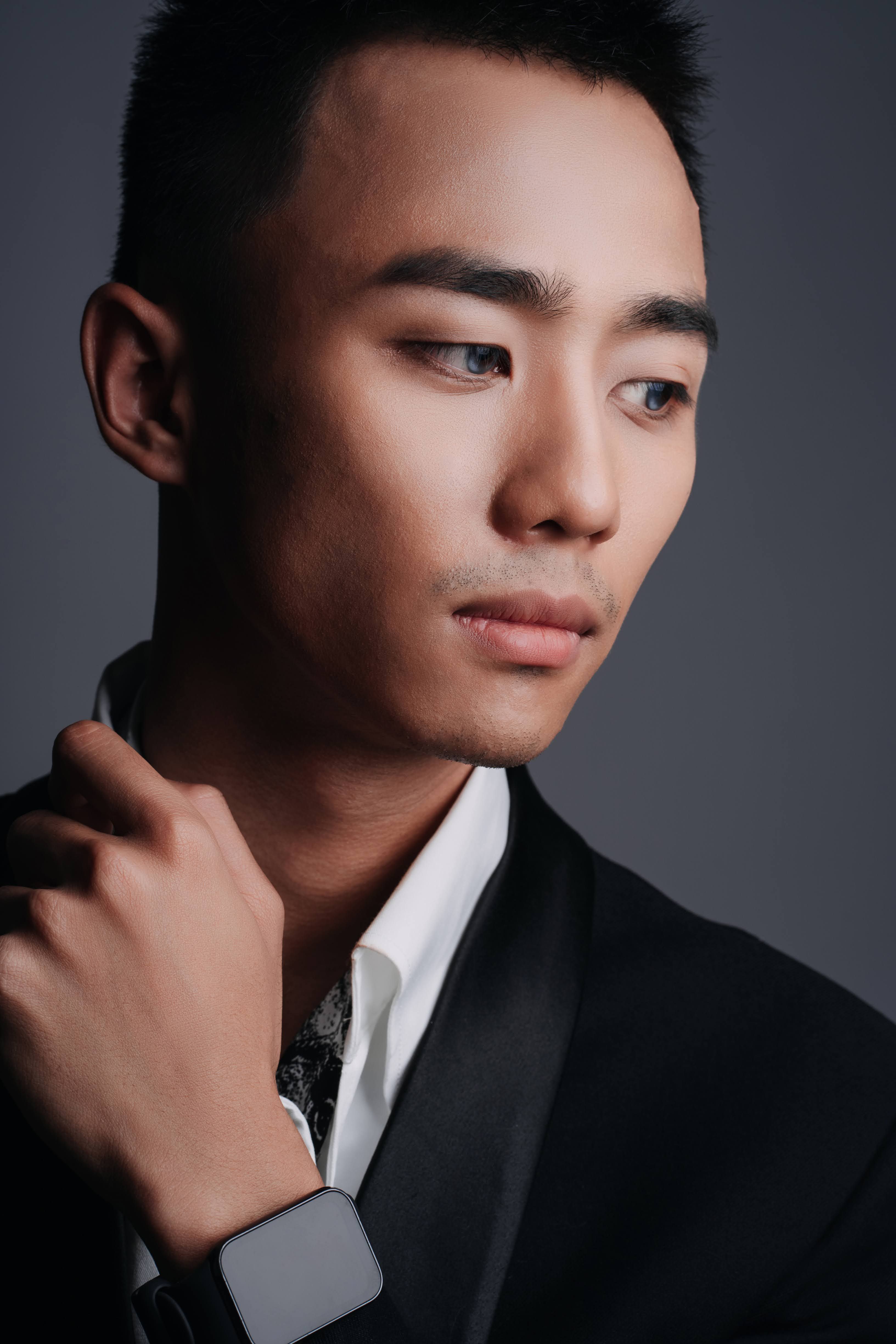 Free A young man in a suit poses thoughtfully, highlighting style with a modern smartwatch. Stock Photo