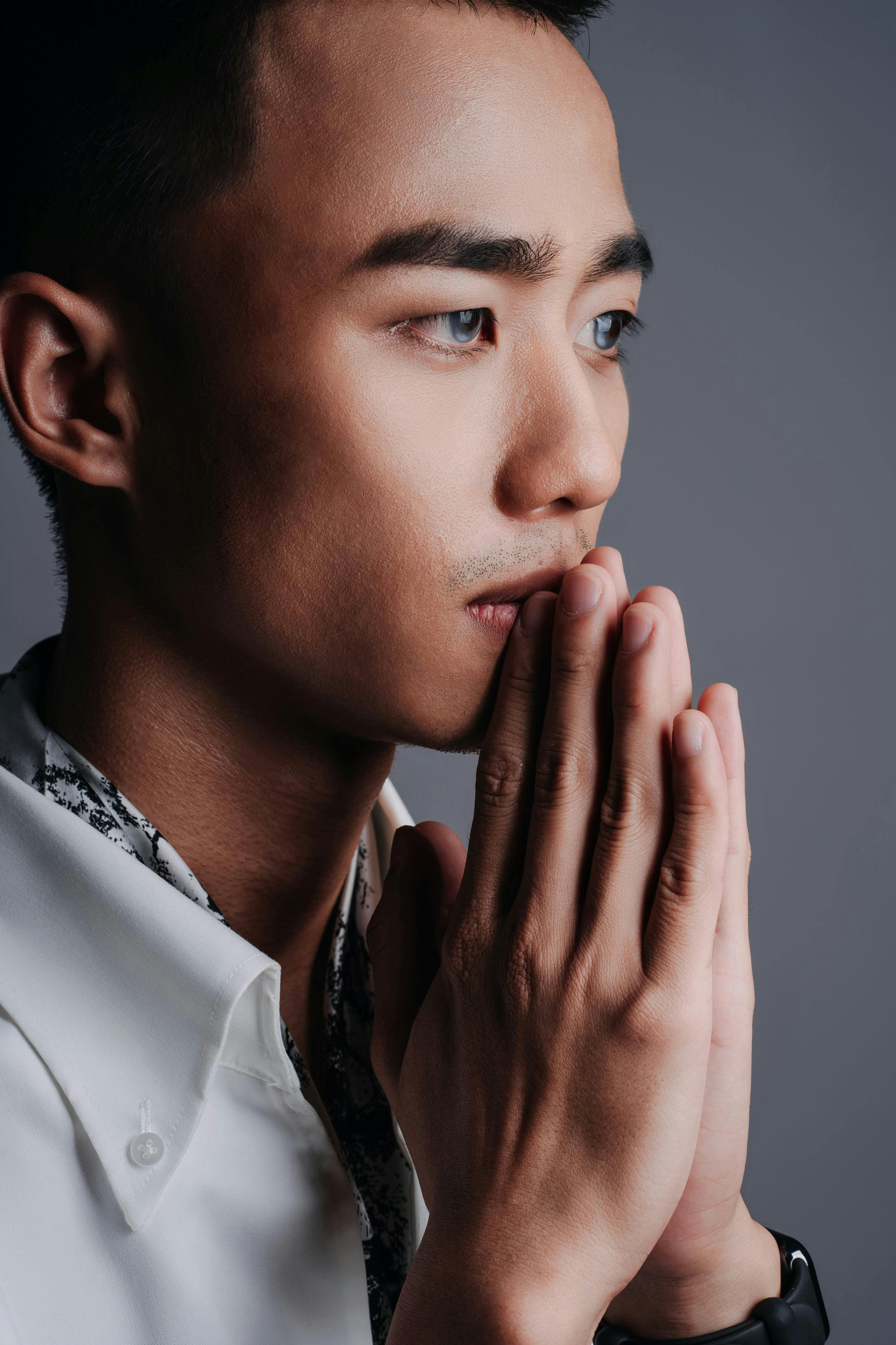 a man in white shirt and black tie praying