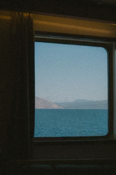 Peaceful view of the Albanian coastline from a ferry window, capturing serene blue waters and clear sky.