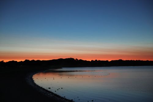 Free A serene sunset over Stamford Beach, capturing reflections and silhouettes against a vibrant sky. Stock Photo