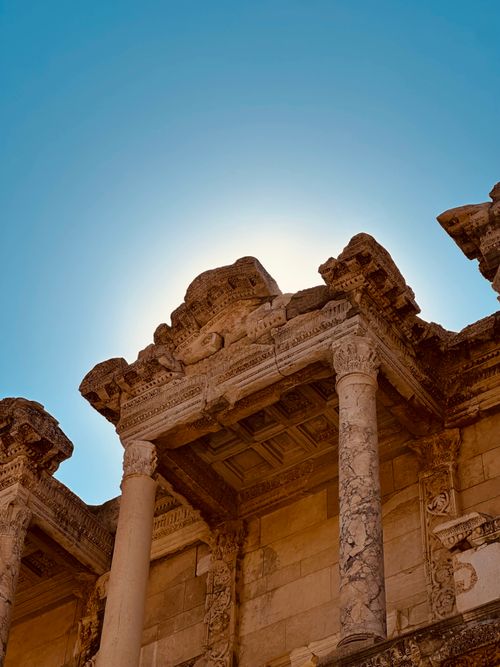 Free Sunlit ancient ruins with detailed stone carvings and columns against a bright blue sky. Stock Photo