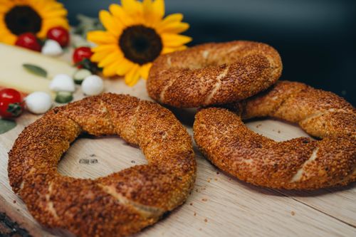 Free Close-up of freshly baked simit rings surrounded by sunflowers and fresh ingredients. Stock Photo