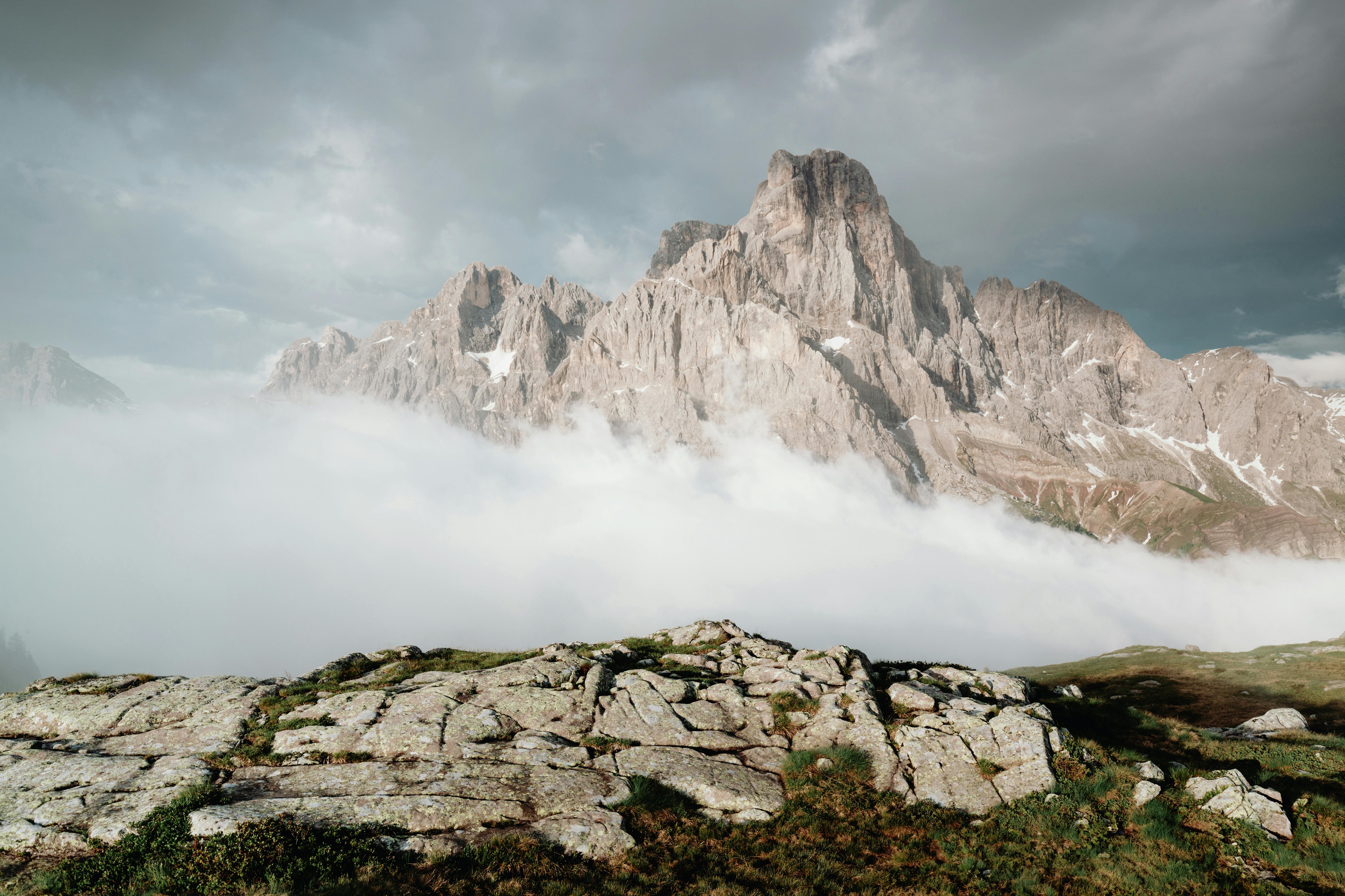 Stunning view of a towering mountain range surrounded by clouds and rocky landscape.