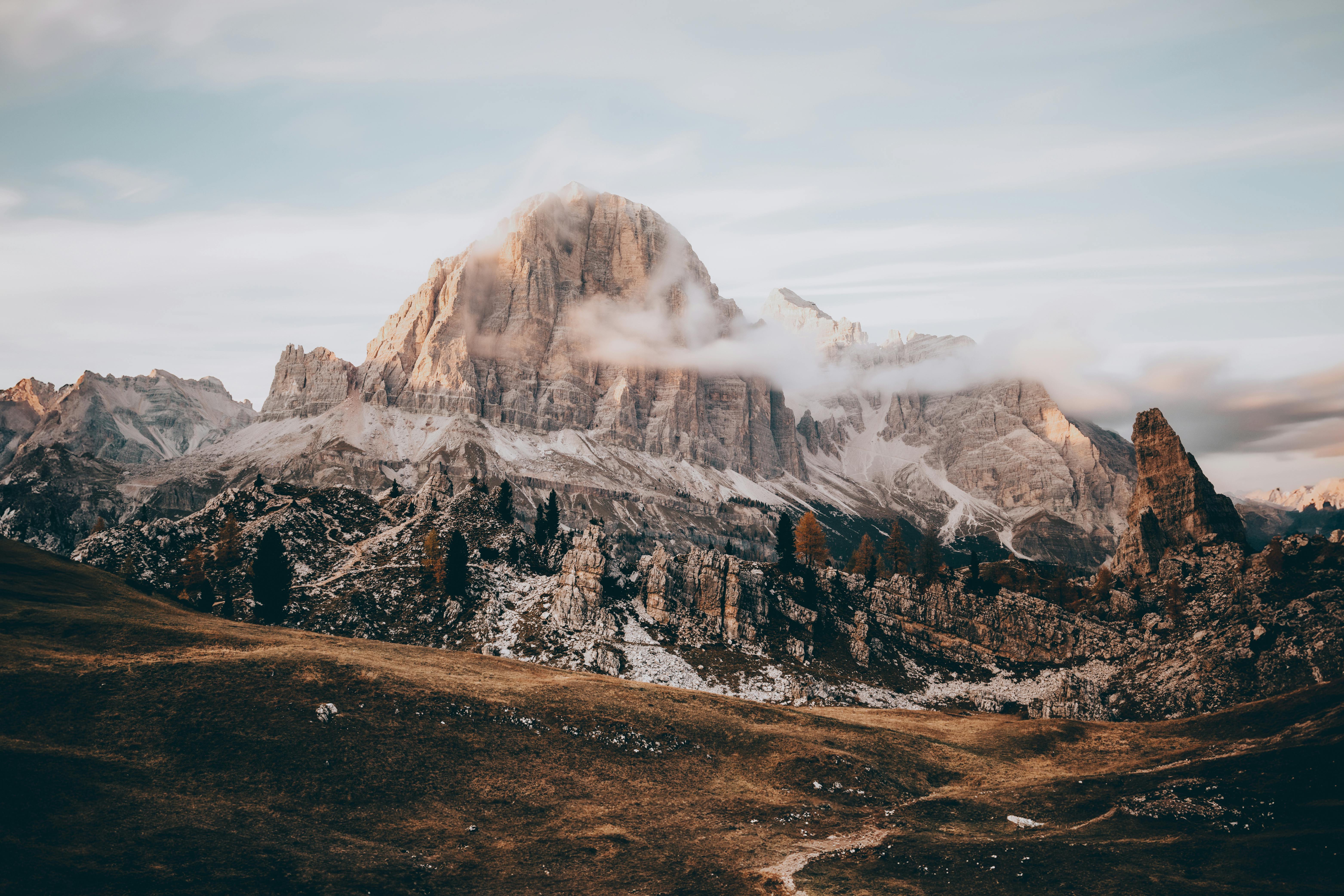 Breathtaking landscape of sunlit mountain peaks and valley with clouds at sunset.