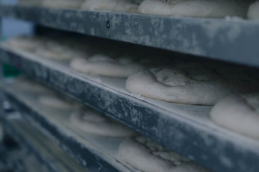 Close-up of fresh dough rising on metal shelves in a bakery setting, showcasing food preparation.
