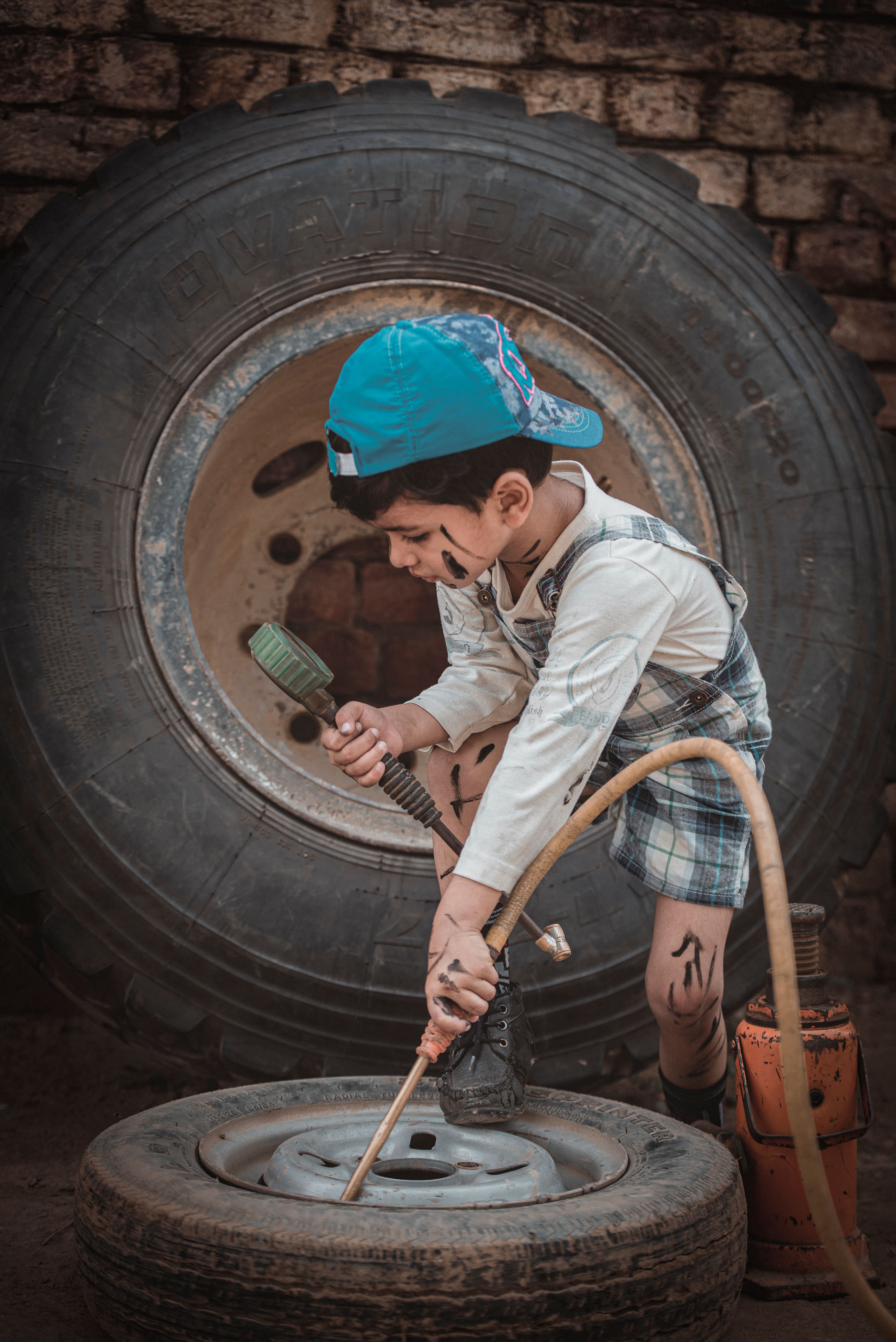 A young boy in a workshop setting is pretending to fix a tire with tools, showcasing imaginative play.