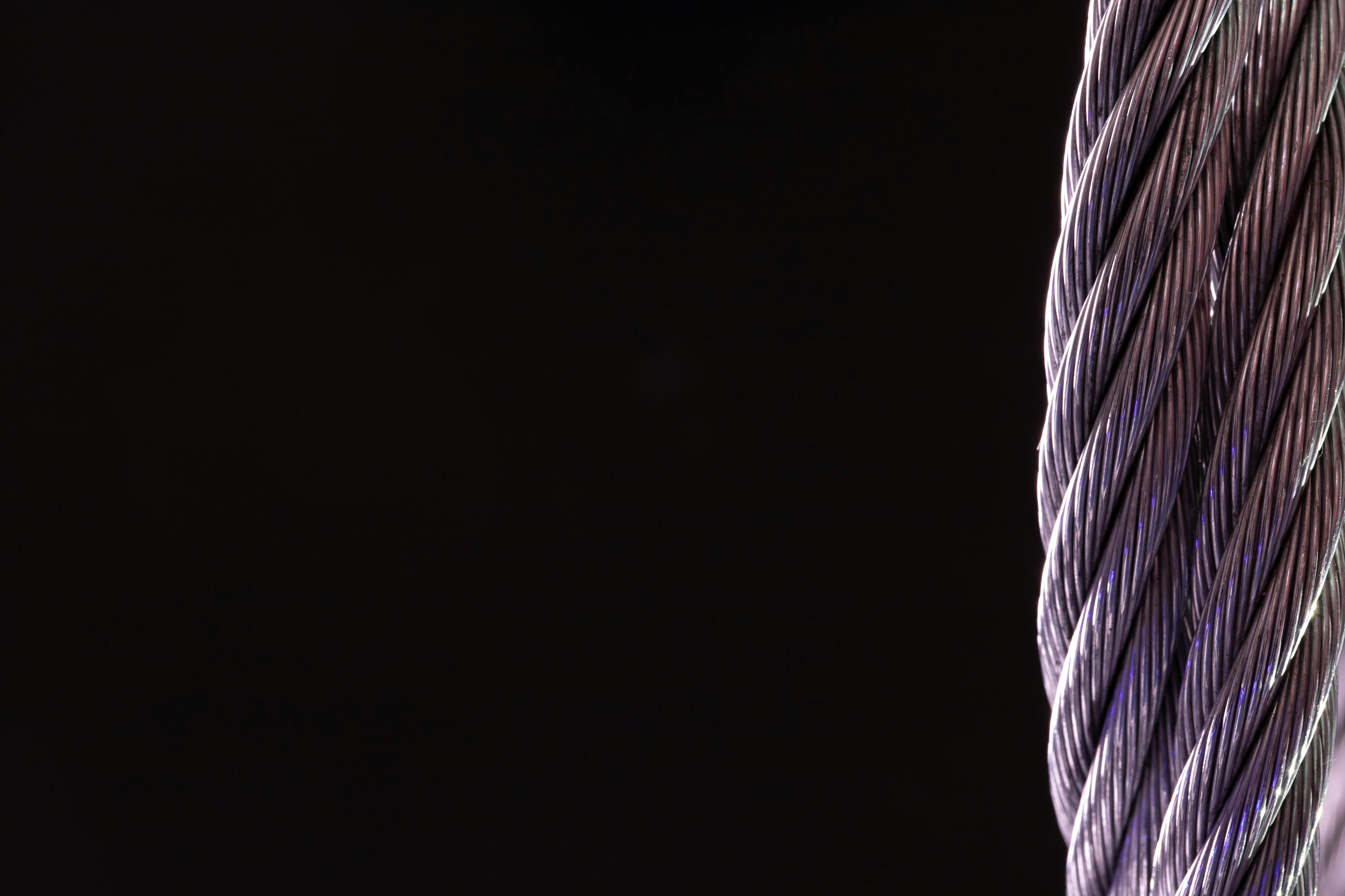 Free Detailed close-up of a silver twisted cable against a black background, perfect for industrial themes. Stock Photo