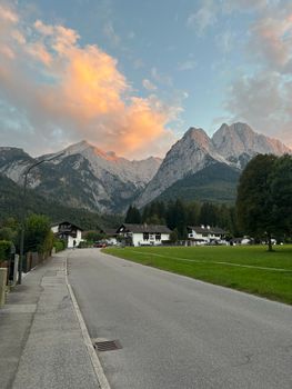 Captivating view of Bavarian Alps with a quiet road and charming houses during sunset.