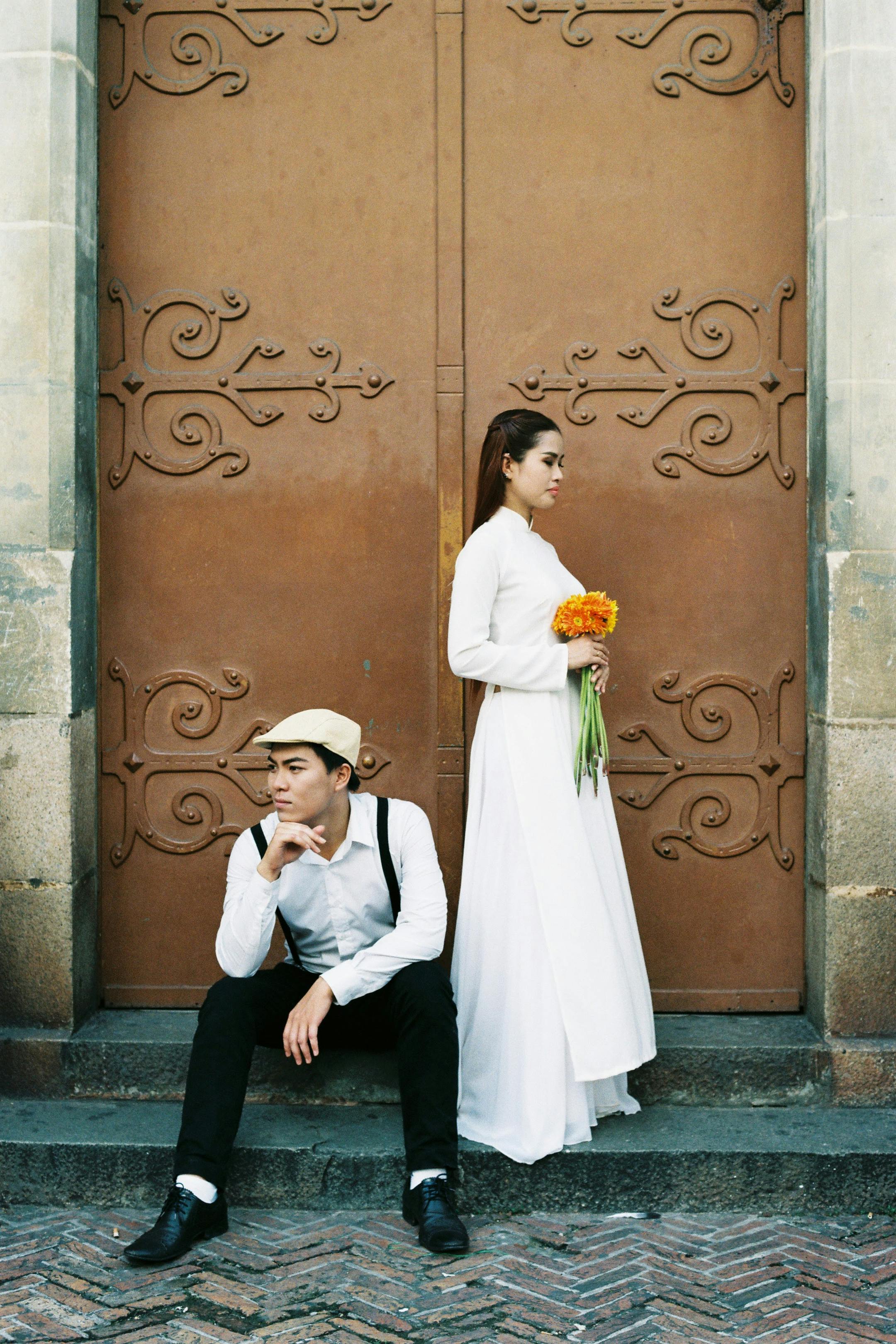 Stylish couple in Vietnamese traditional and modern attire posing in urban Ho Chi Minh City.